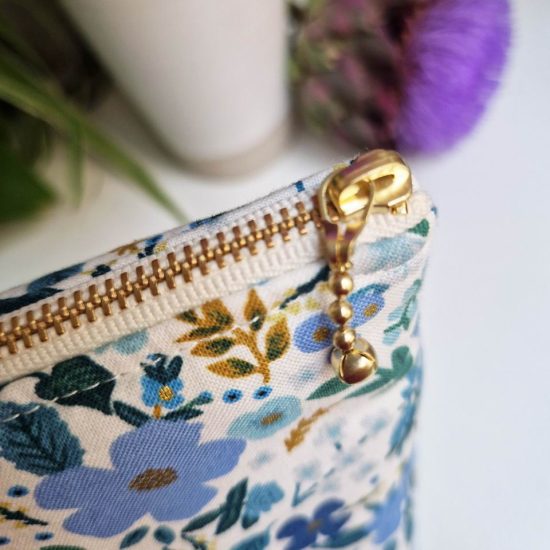 Détail chic et raffiné le zip doré pour cette trousse en tissu molletonné motif floral bleu sur fond blanc