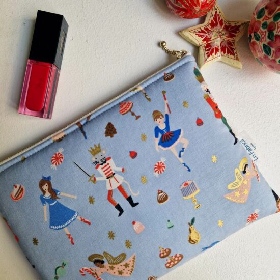 Pochette en tissu rifle paper co imprimé personnages multicolores rouge blanc bleu or métallisé de Noël sur un fond bleu lavande